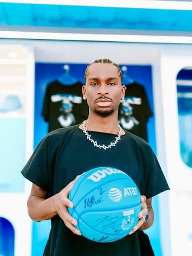 A guest holds a signed Wilson AT&T basketball in front of the Dunk Bus merch wall