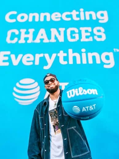 A guest in sunglasses spins an AT&T basketball under the Connecting Changes Everything sign