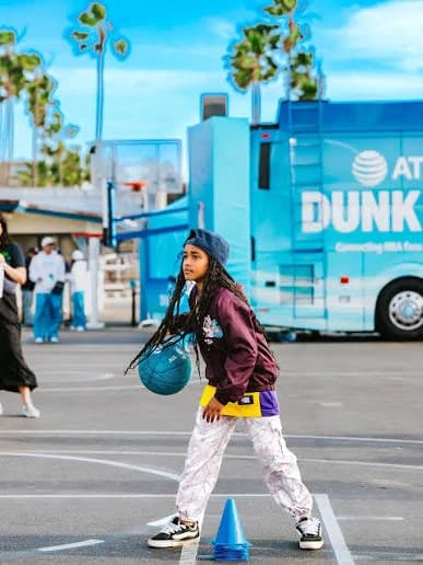 A young player dribbles past cones beside the AT&T Dunk Bus